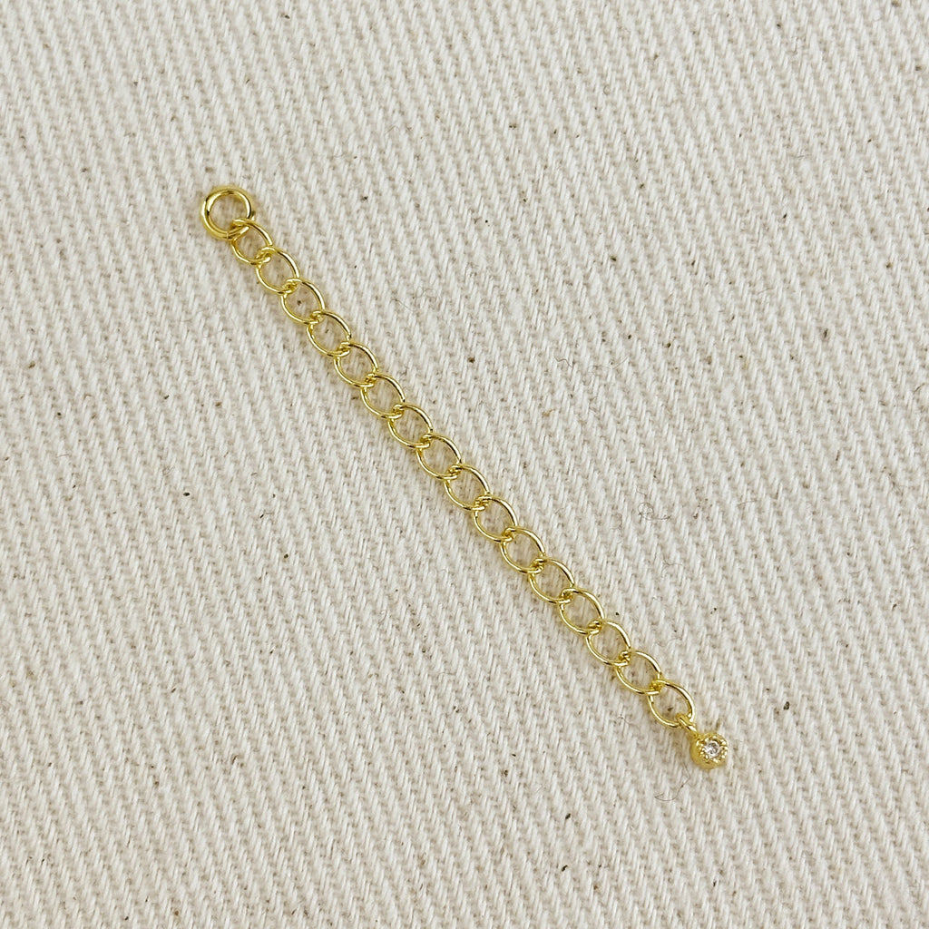 Gold chain extender accessory on a beige fabric background