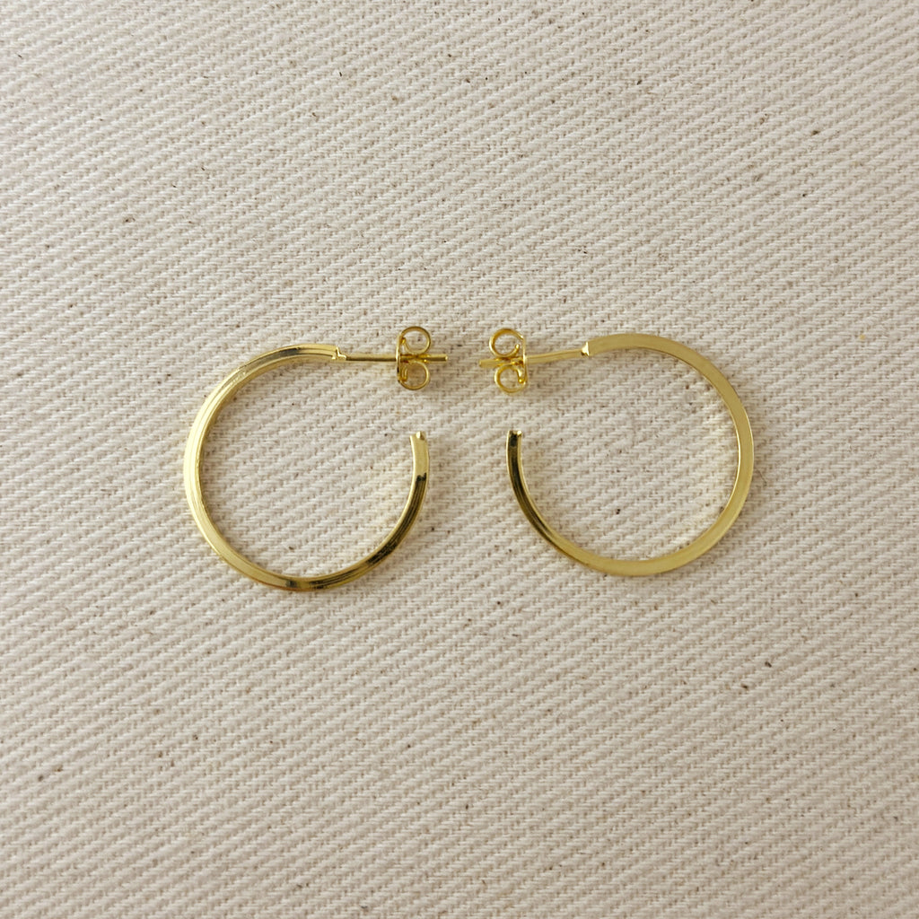Gold hoop earrings on a beige fabric background