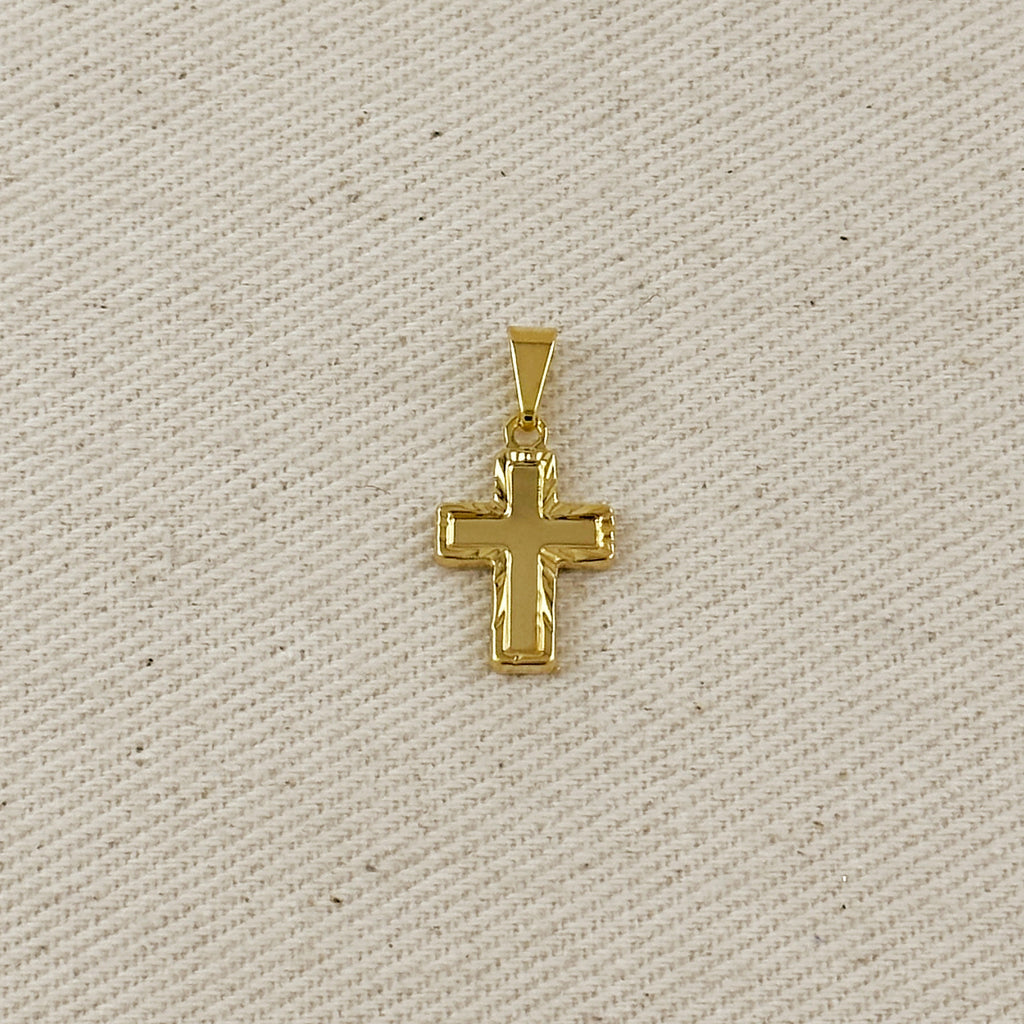 Gold cross pendant on a beige fabric background