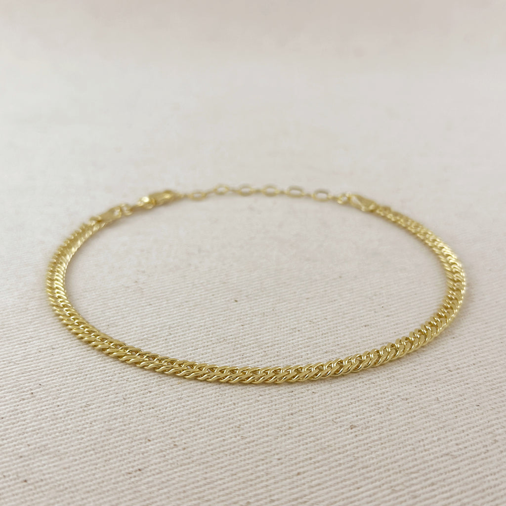 Gold chain bracelet on a light beige fabric background