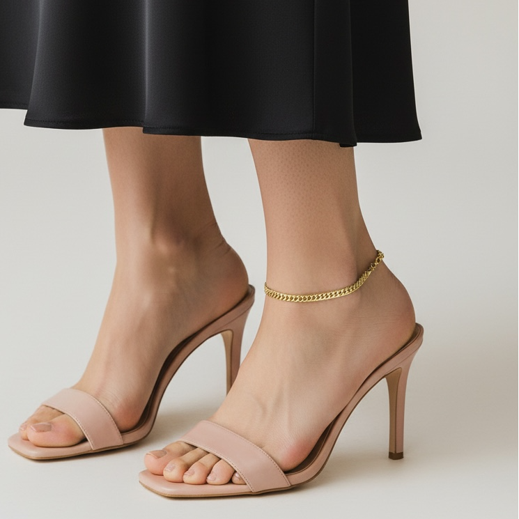 Beige high-heeled sandals worn with a black skirt on a neutral background