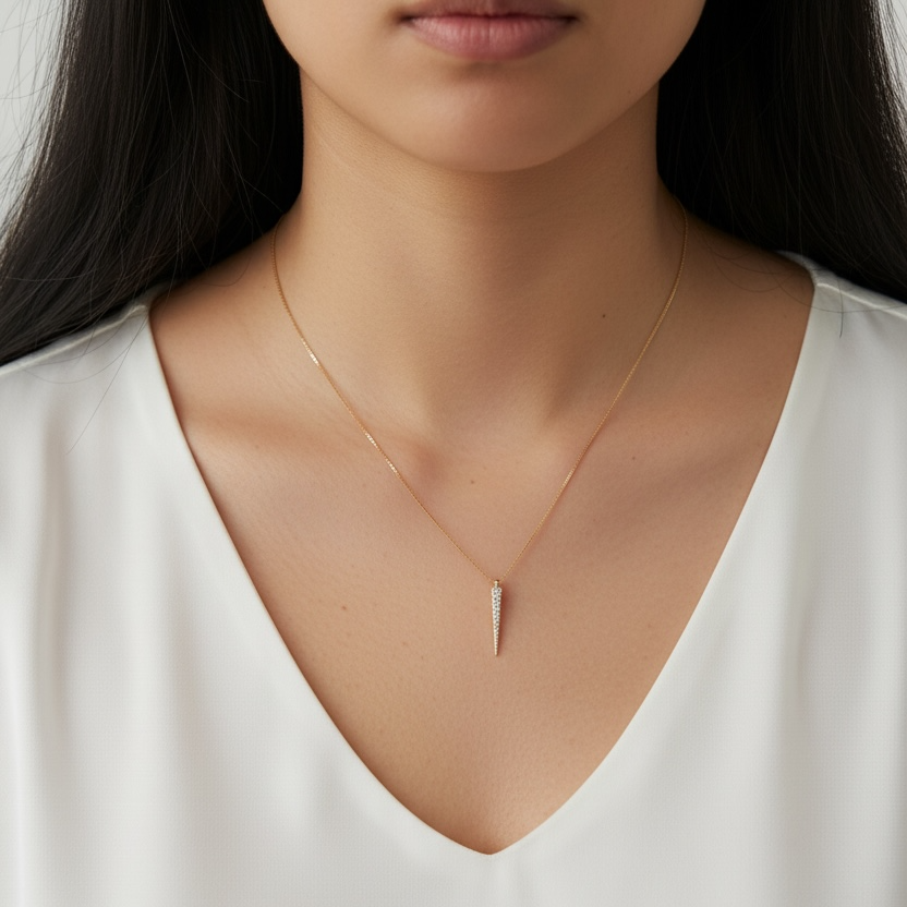 Woman wearing a delicate gold necklace with a minimal pendant on a plain background