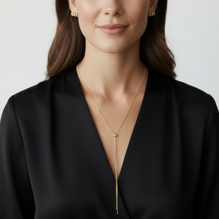 Woman wearing a black outfit with a gold necklace against a plain background