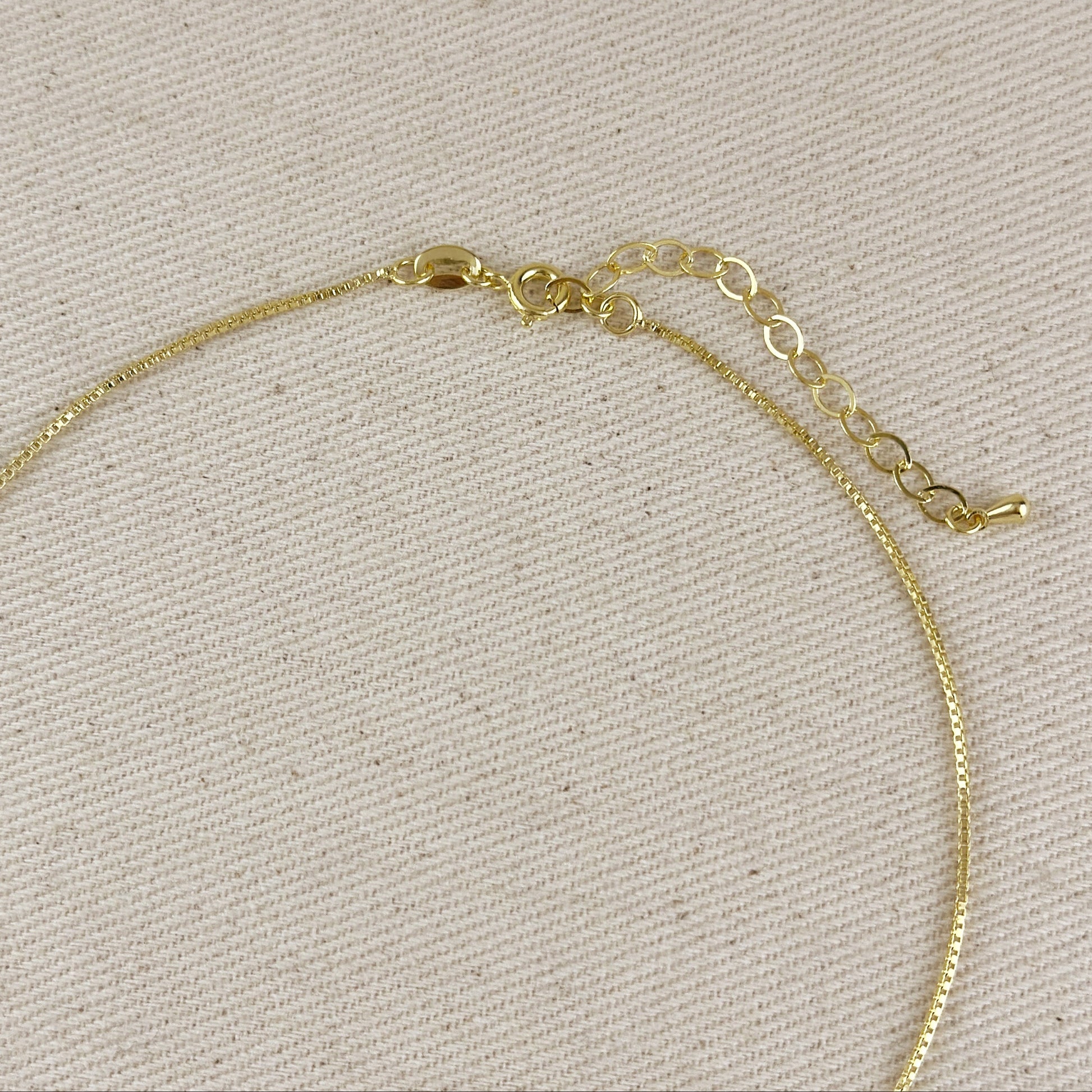 Gold necklace on a beige fabric background