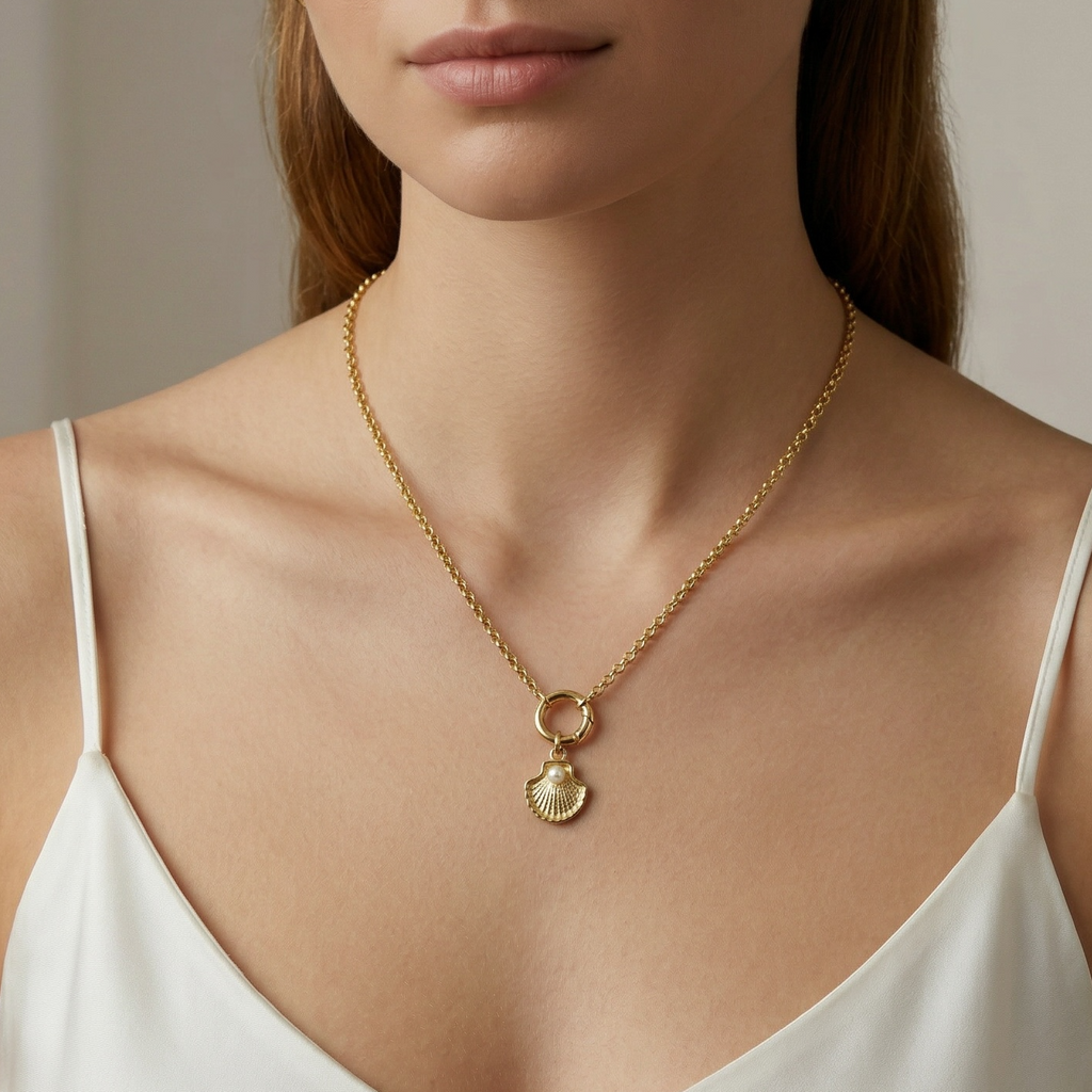 Woman wearing a gold necklace with a shell pendant against a neutral background