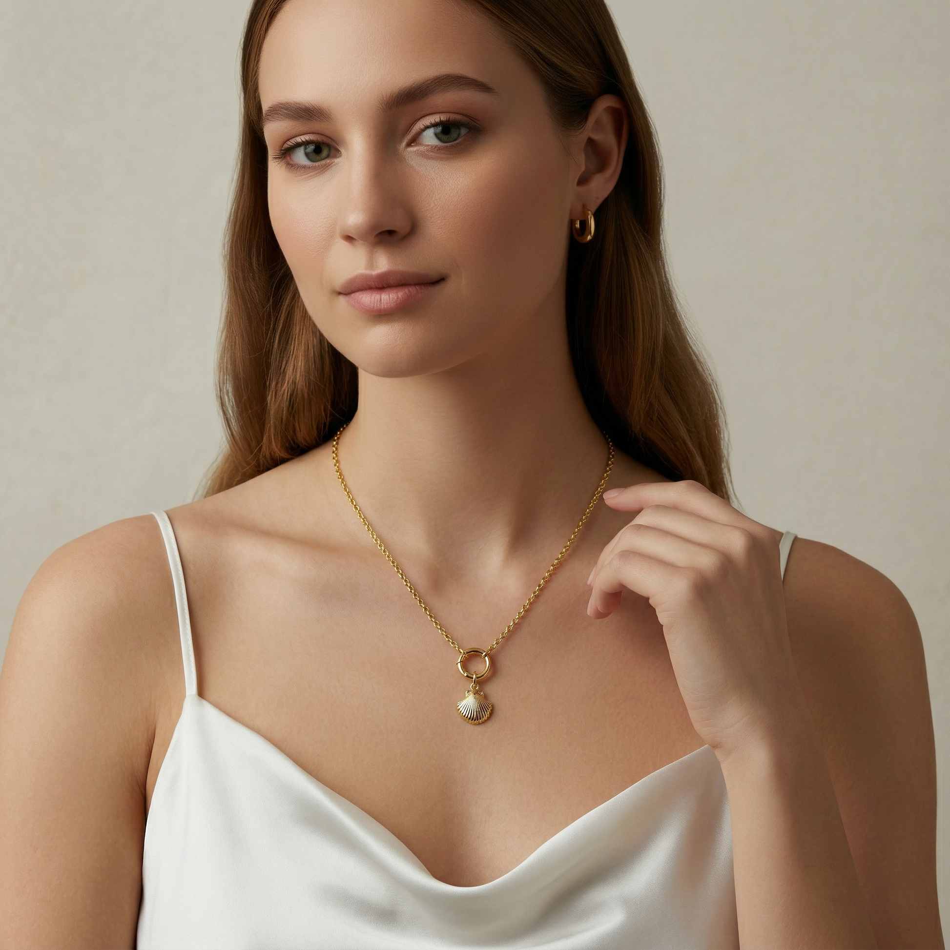 Woman wearing a gold necklace and earring set against a neutral background
