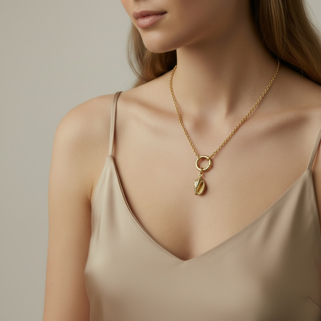 Woman wearing a gold necklace with a conch pendant against a neutral background
