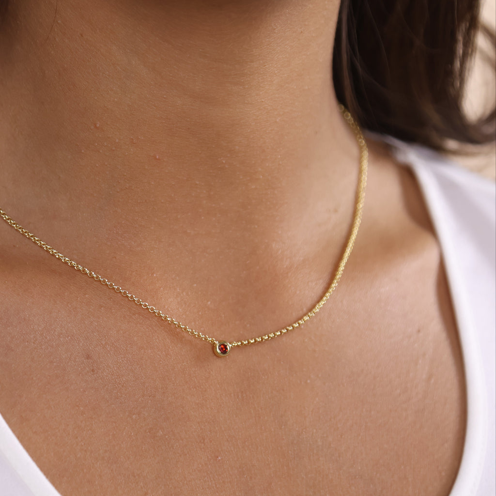 Gold necklace on a person wearing a white top