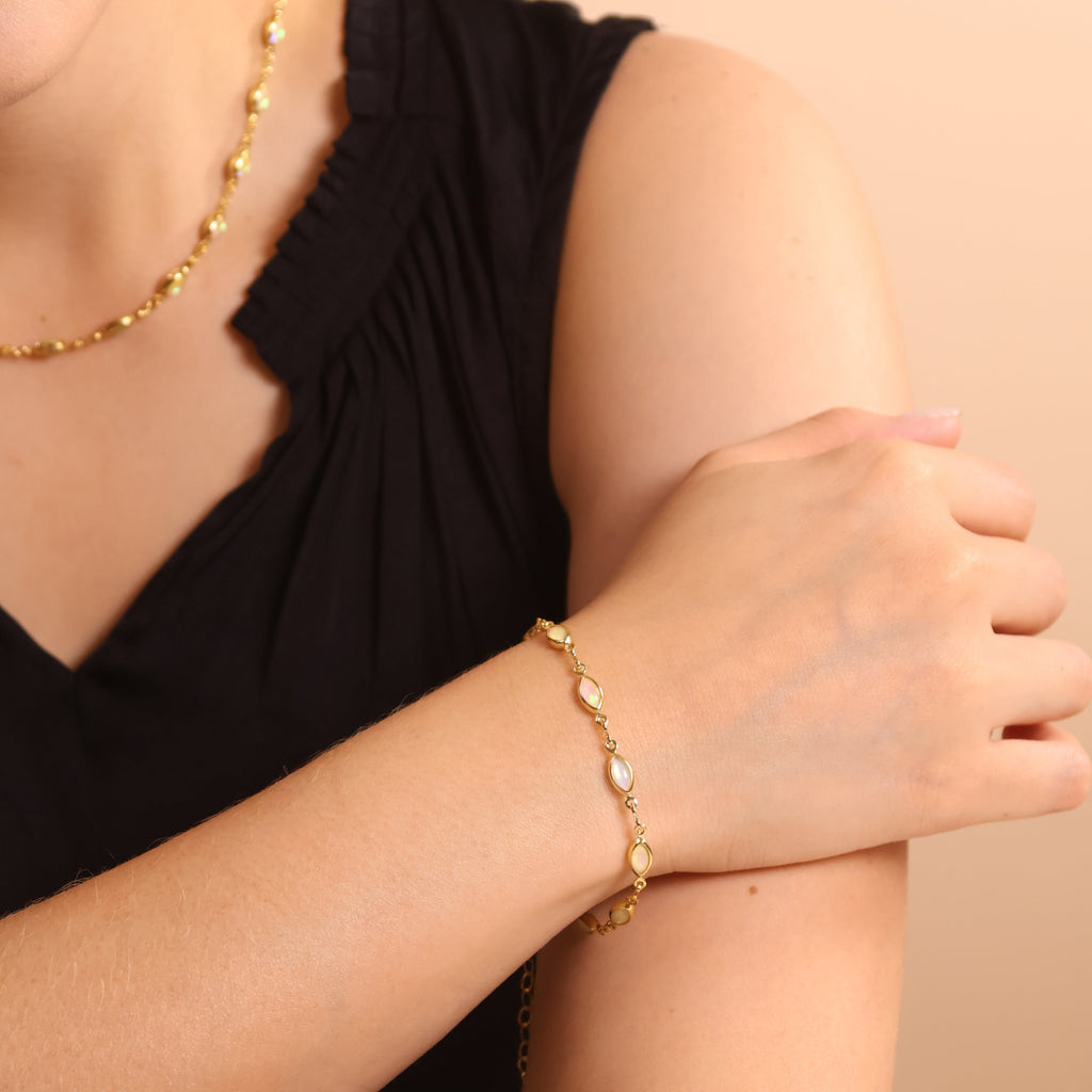 Woman wearing a gold bracelet and necklace on a beige background