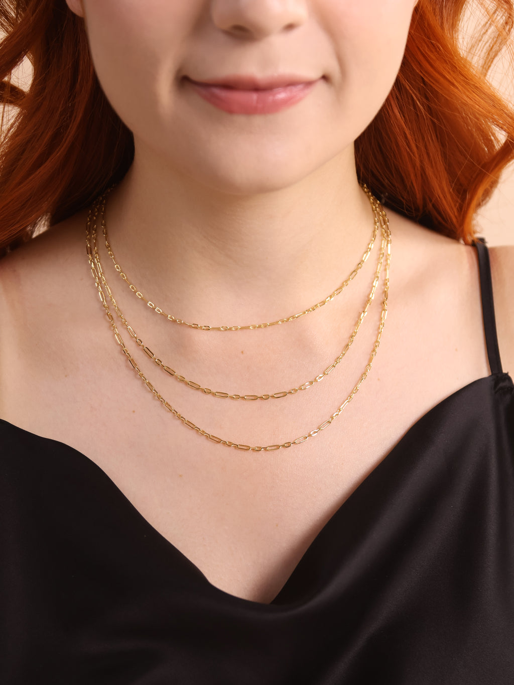 Close-up of a person wearing two gold necklaces with a blurred background