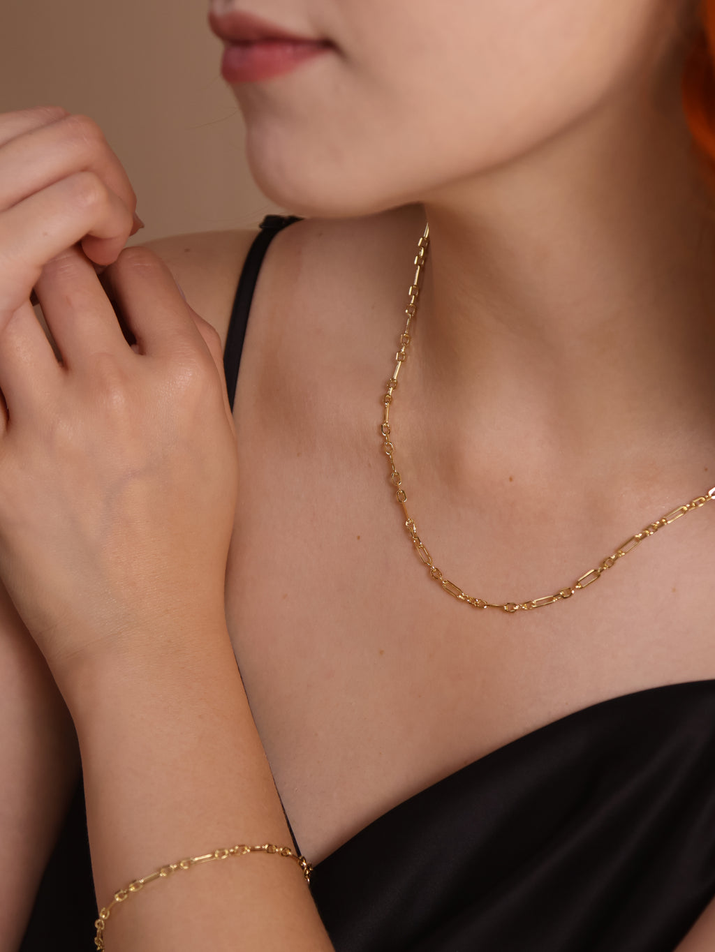 Model wearing an 18k gold filled 3x1 alternated paperclip necklace and bracelet, showcasing contemporary jewelry style.