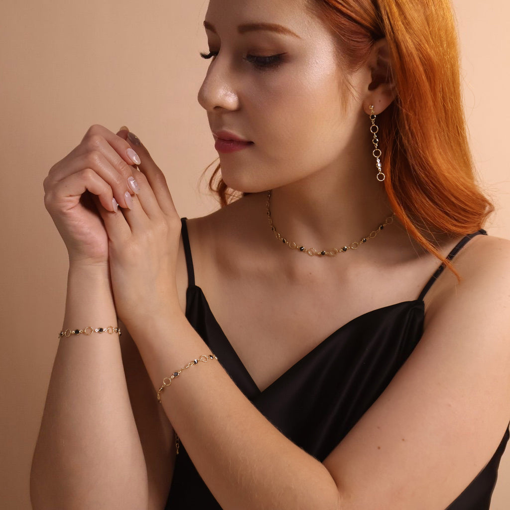 Woman wearing gold jewelry against a beige background