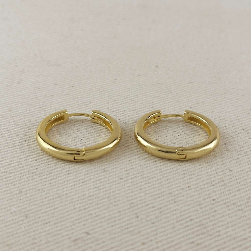Pair of gold hoop earrings on a beige fabric background