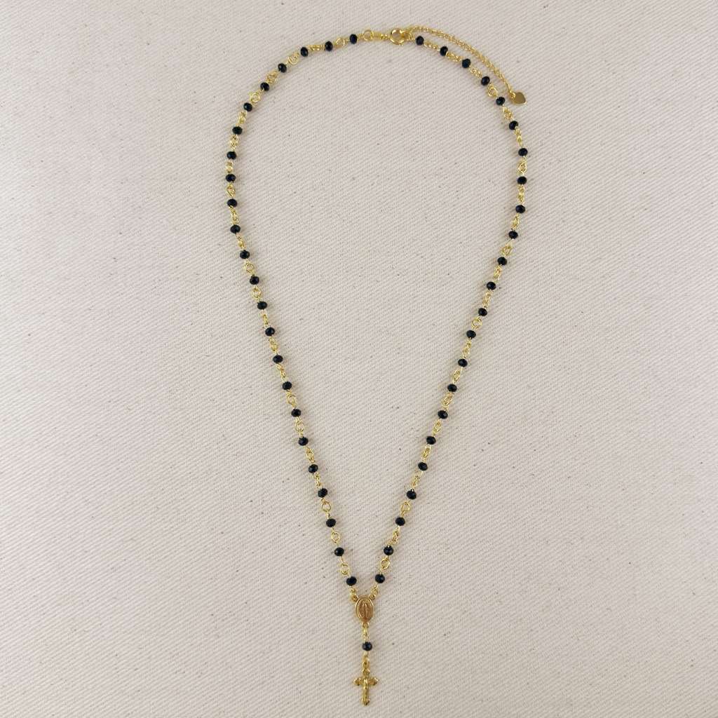 Necklace with black and gold beads and a cross pendant on a light gray background